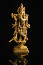 Krishna god Vishnu avatar brass statue isolated on black with reflection