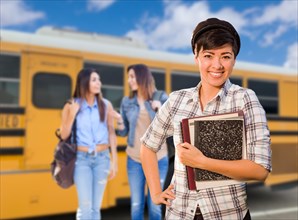 Young mixed-race female students near school bus