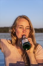 Junge Frau trinkt Bier aus einer Flache