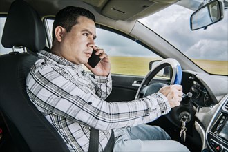 A man driver calling on the phone in his car