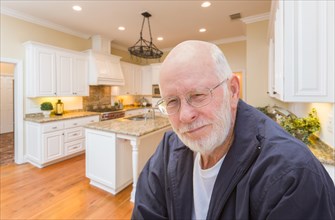 Happy senior man sitting in custom kitchen interior