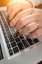 Male hands typing on laptop computer keyboard