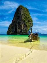 Long tail boat on tropical beach with limestone rock