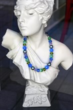 Ceramic bust of the hetaera Thais with necklace in shop window
