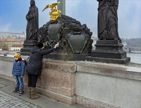 Praying woman with child on Charles Bridge