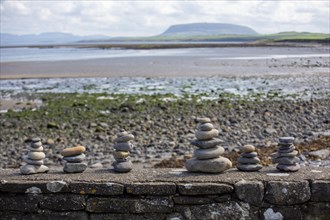 Columns of pebbles on a stone wall in Ireland with a view of Knocknarea in the background. Sligo