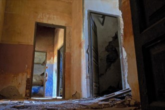 Empty devastated rooms of an abandoned house with coloured walls