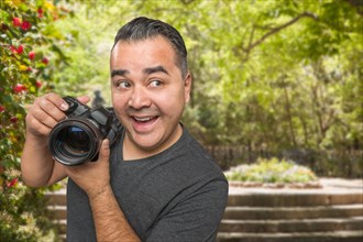 Hispanic young male photographer with DSLR camera outdoors