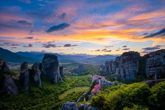 Sunset sky and monastery of Rousanou and Monastery of St. Nicholas Anapavsa in famous greek tourist destination Meteora in Greece with sun rays and lens flare