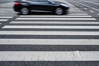 Crosswalk pedestrian crossing with blurred car on asphalt road in the street