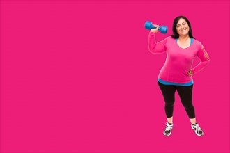 Middle aged hispanic woman in workout clothes holding dumbbell against A bright magenta pink background