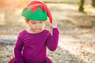 Cute mixed-race young baby girl having fun wearing christmas hat outdoors
