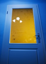 Verschlossene blaue Glastuere mit einer Deckenbeleuchtung in einem Wohnhaus