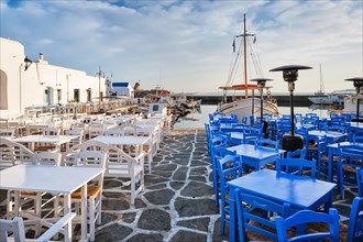 Cafe tables on quay of Naousa town port in famous tourist attraction Paros island