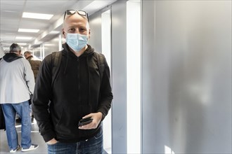 A tourist wearing a protective mask and backpack waiting on the airport to be boarded
