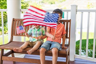 Young mixed-race chinese and caucasian brothers playing with american flags