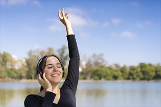 Young woman listening to music outdoors with headphones. Expression of happiness
