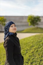 Portrait of a Latin woman undergoing cancer treatment with her head covered by a scarf with an expression of strength