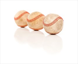 Three baseballs isolated on a reflective white background