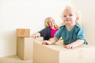 Playful happy mother and son in empty room with moving boxes