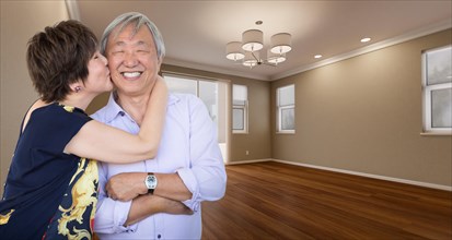 Two affectionate chinese senior adults in new empty room of house