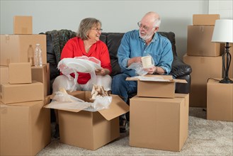 Senior adult couple packing or unpacking moving boxes