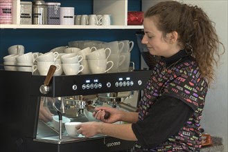 Junge Frau bereitet Kaffee an einer Espressomaschine in einem Cafe