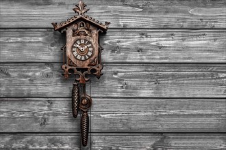 Antique Black Forest cuckoo clock in front of black and white wooden wall