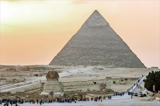 View of Sphinx of Giza and Great Pyramid of Chepos at dusk with tourists