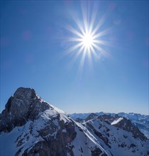 Strahlende Sonne und blauer Himmel ueber Winterlandschaft und schneebedeckte Alpengipfel