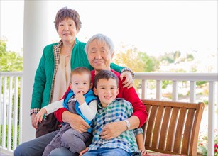 Senior adult chinese couple sitting with their mixed-race grandchildren