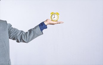 A hand holding a table clock on isolated background