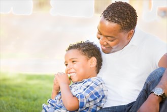 African american father and mixed-race son eating an apple in the park