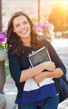Portrait of pretty young female student carrying books on school campus
