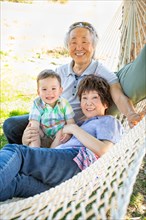 Chinese grandparents in hammock with mixed-race child
