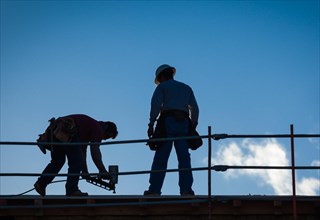 Construction workers silhouette on roof of building