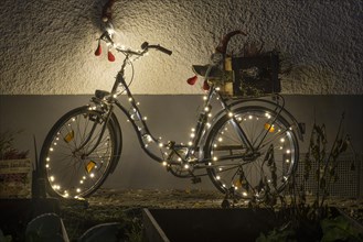 Christmas illuminated bicycle in front of a house wall