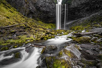 Young woman standing in front of waterfall