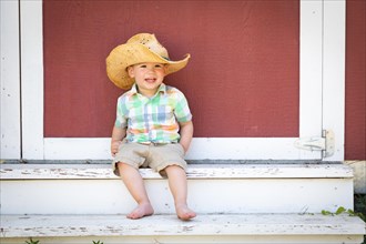 Young mixed-race chinese and caucasian boy wearing cowboy hat relaxing on the steps