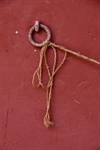 Metal ring on red wall with tied long cord