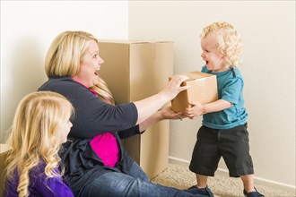 Playful young family in empty room playing with moving boxes