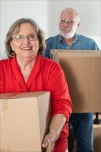 Senior adult couple carrying moving boxes