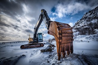 Old excavator with excavator bucket in winter. Road construction in snow. Lofoten islands