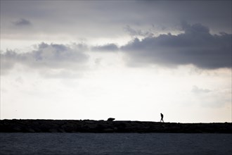 Person backlit on coastal fortification in San Lorenzo al Mare