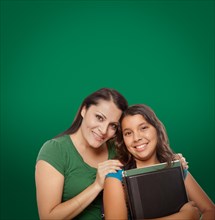Blank chalk board behind proud hispanic mother and daughter student