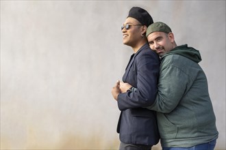 Gay latin couple wearing fashionable hats hugging in the street. Copy space