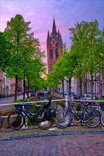 Delt street with bicycles on bridge over canal on sunset in dusk. Delft