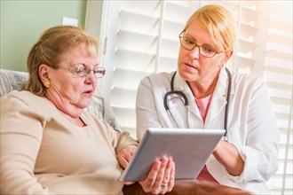 Doctor or nurse talking to senior woman with touch pad computer