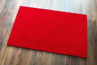 Blank red welcome mat on wood floor background ready for your own text