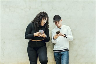 Two teenagers together checking their cell phones